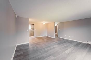 A living room and dining room of an empty house with wood flooring